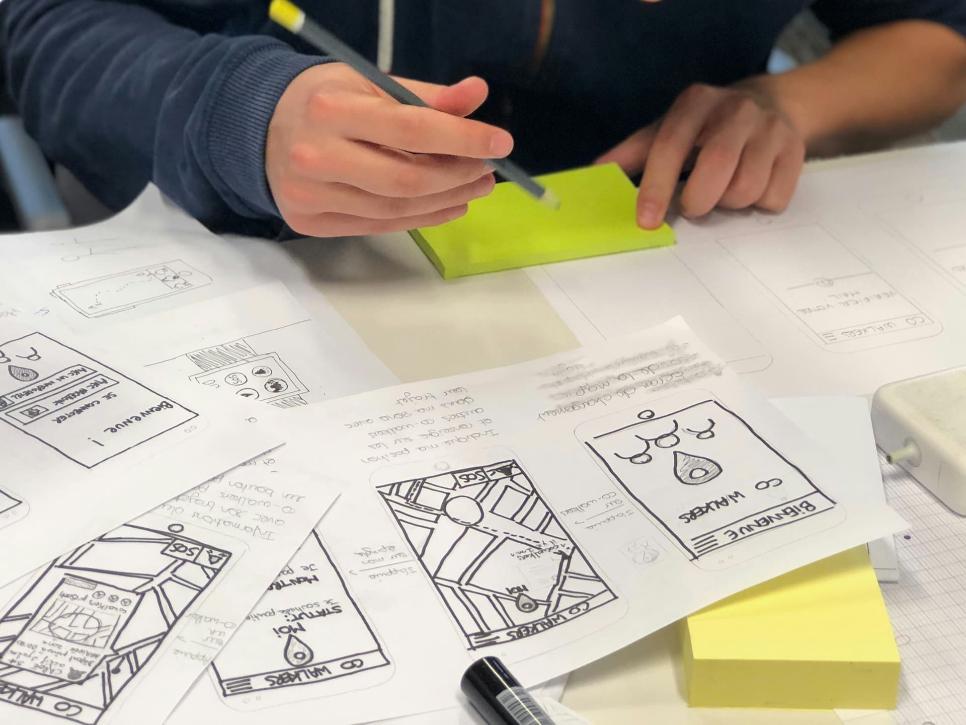 Designer sketching mobile app wireframes on paper while mapping the product and user journey